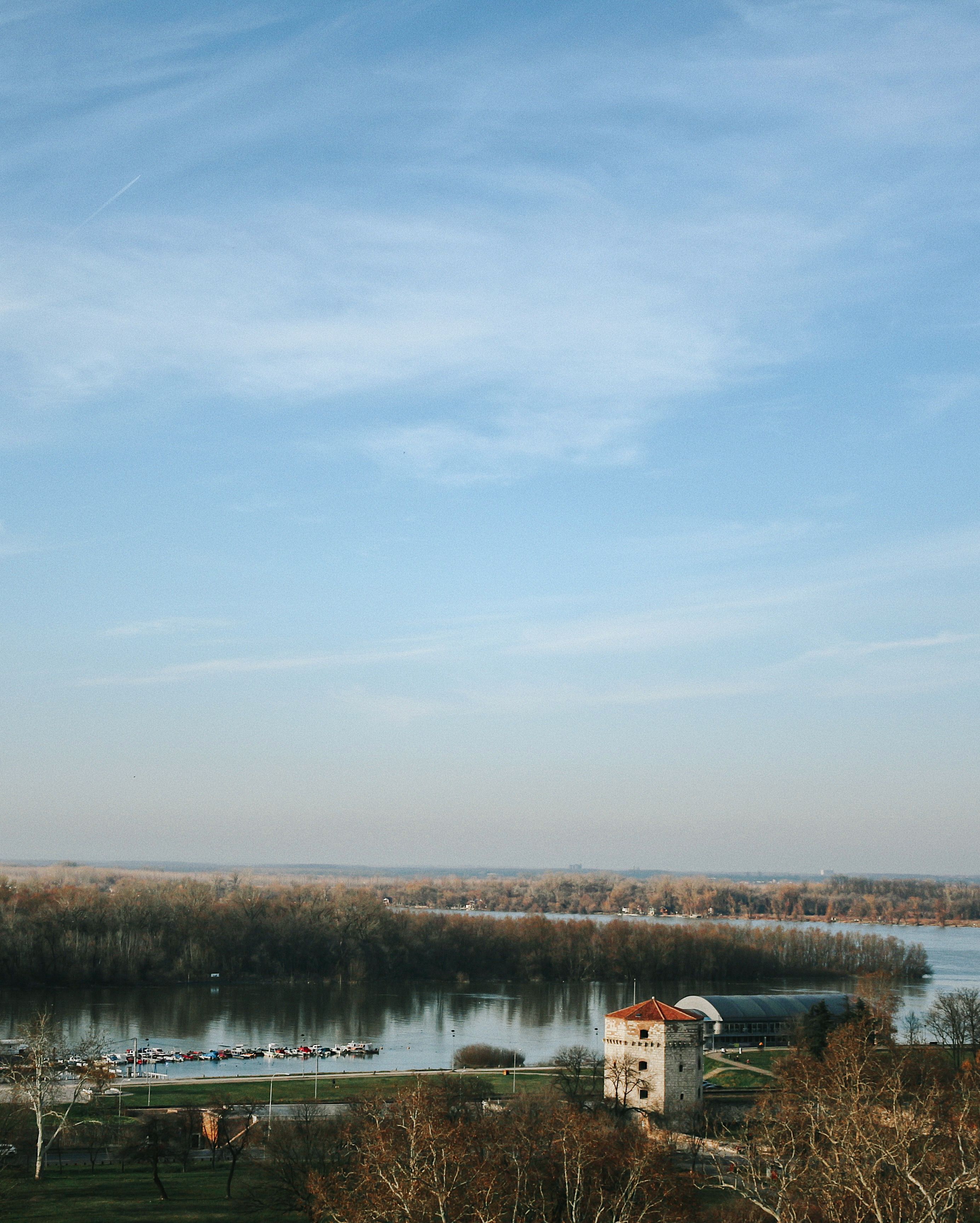 White and Brown House Near Body of Water Under Blue Sky · Free Stock Photo
