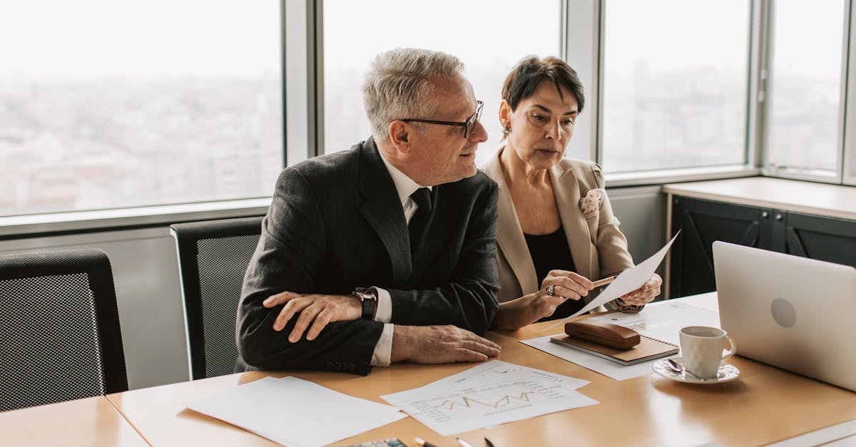 Two business professionals analyzing financial papers in a modern office setting.