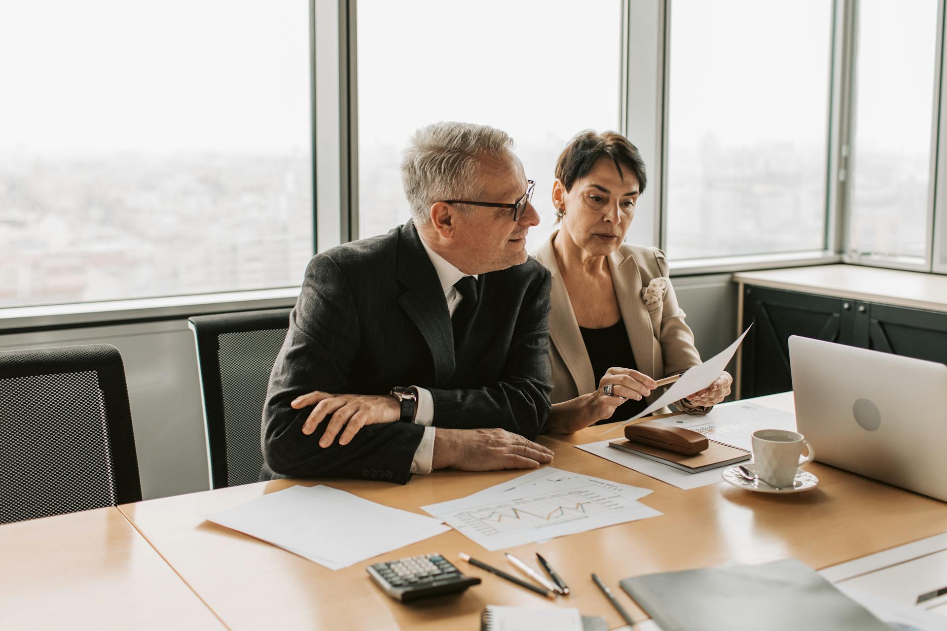 Two business professionals analyzing financial papers in a modern office setting.