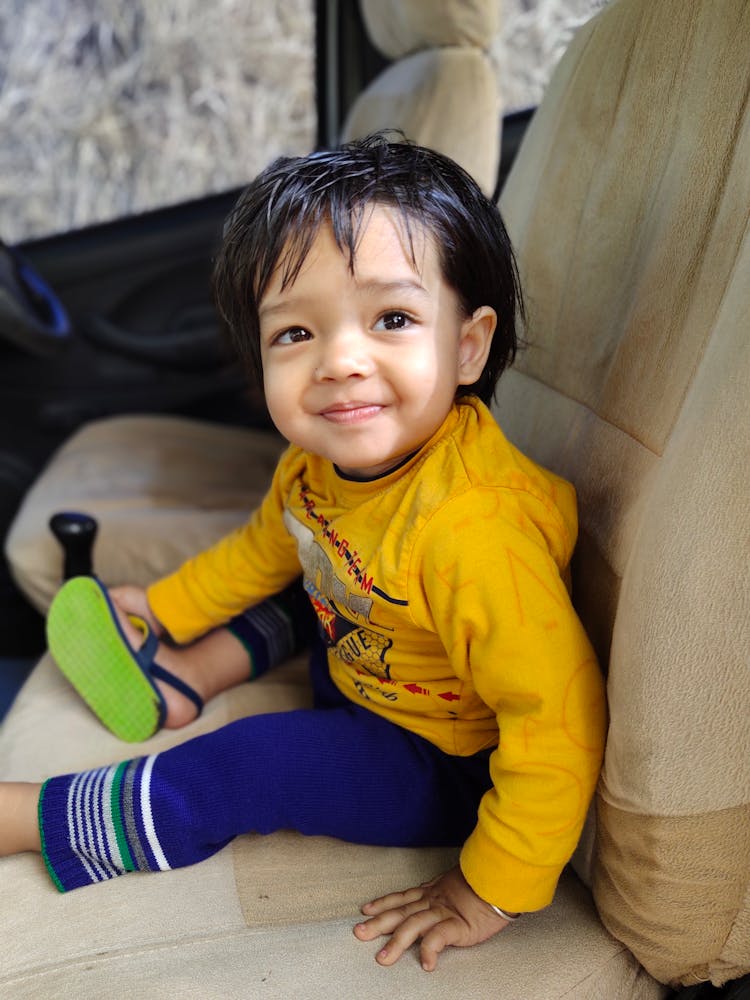 A Smiling Little Boy Sitting Inside A Car