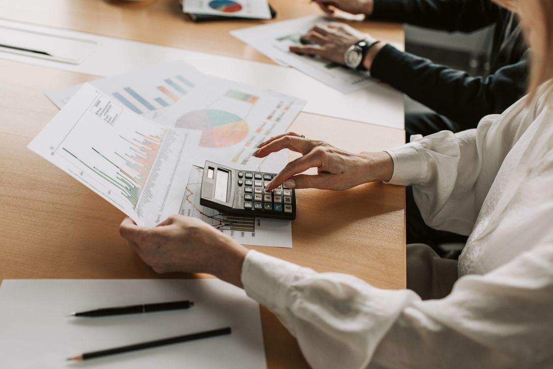 Análise financeira de gráficos e custos com calculadora em mesa de reunião