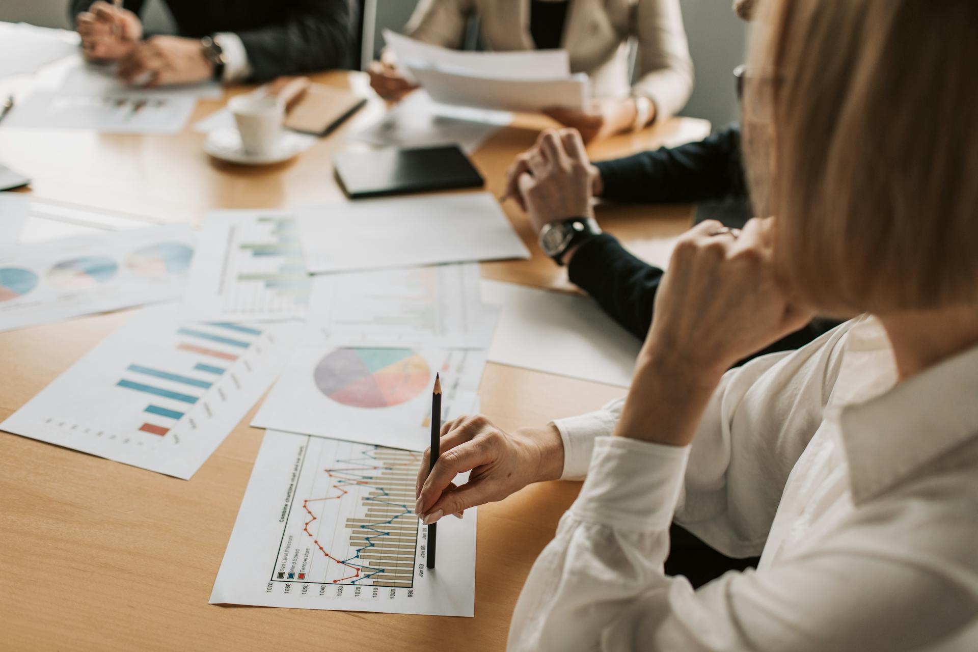 Business professionals reviewing charts and graphs during a meeting in office setting.