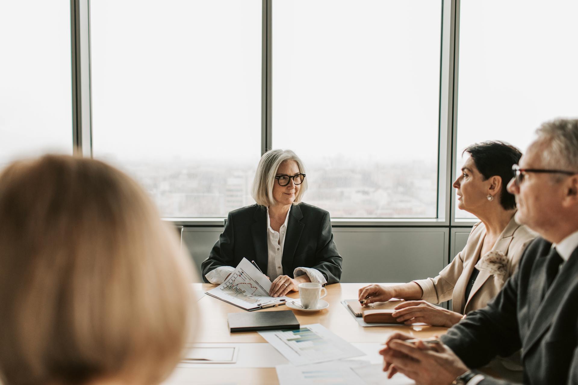 A group of professionals engaged in a business meeting inside a modern office boardroom.