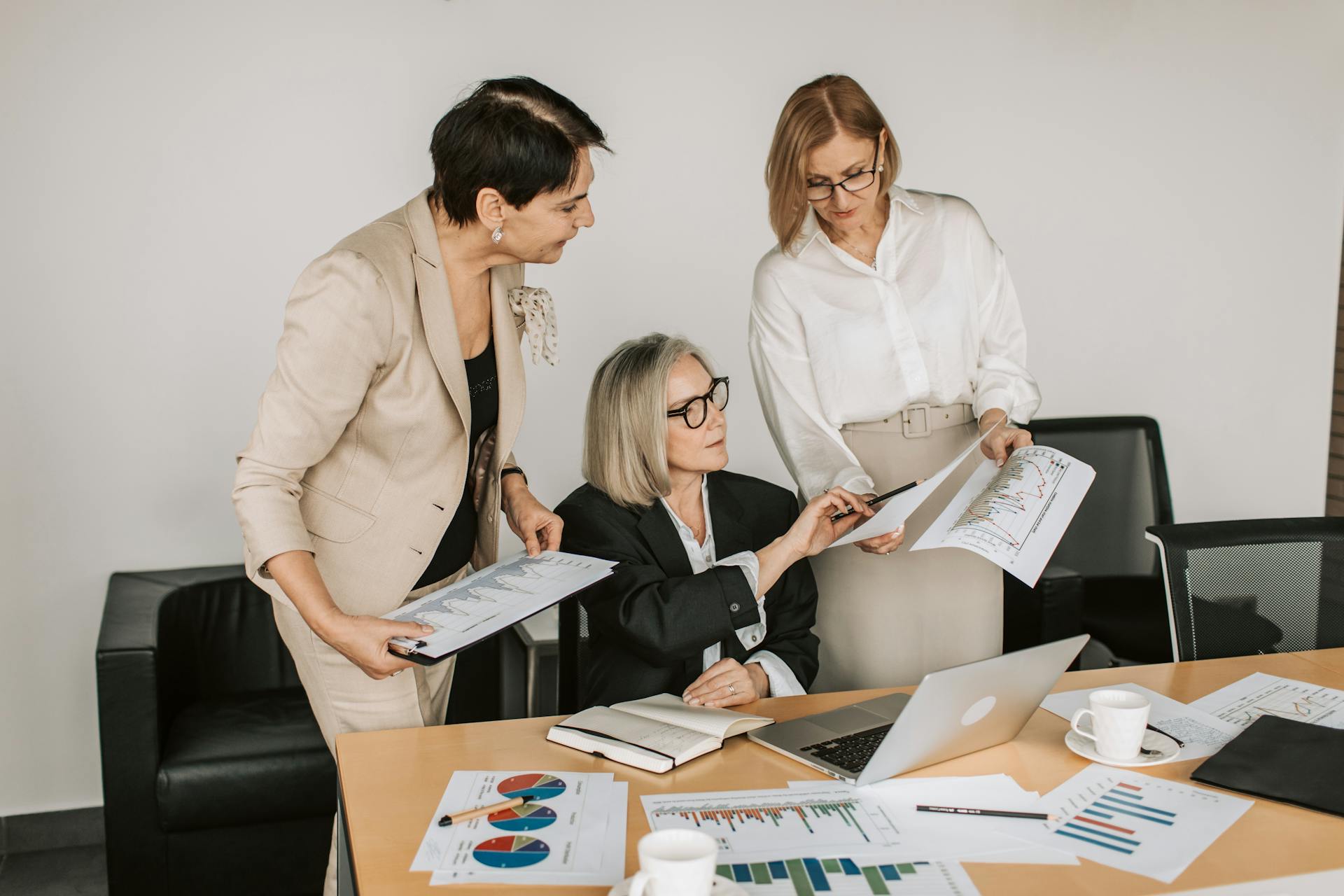 Group of senior businesswomen discussing financial charts during a formal meeting.