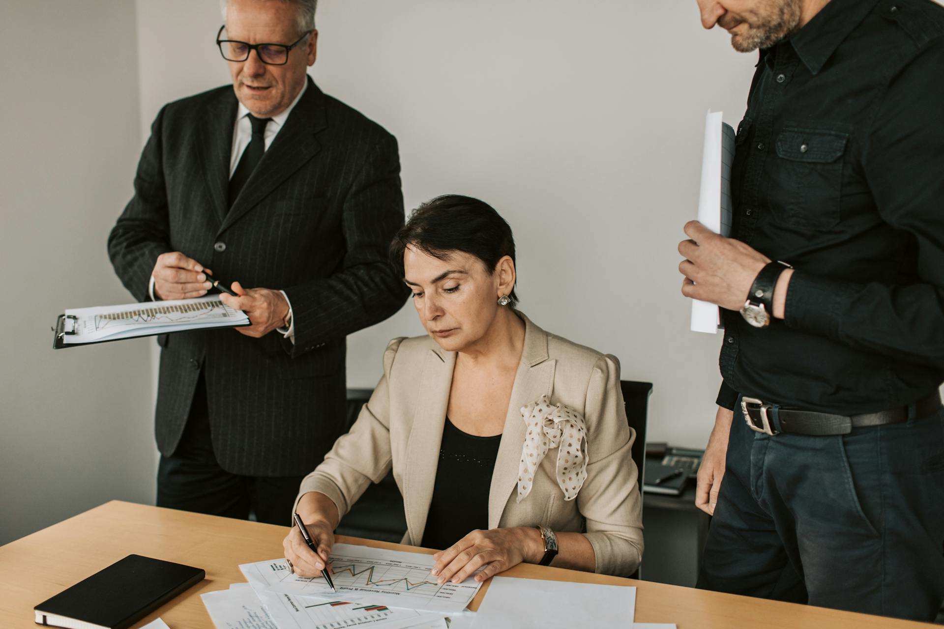 Business professionals collaborating on financial documents in an office setting.