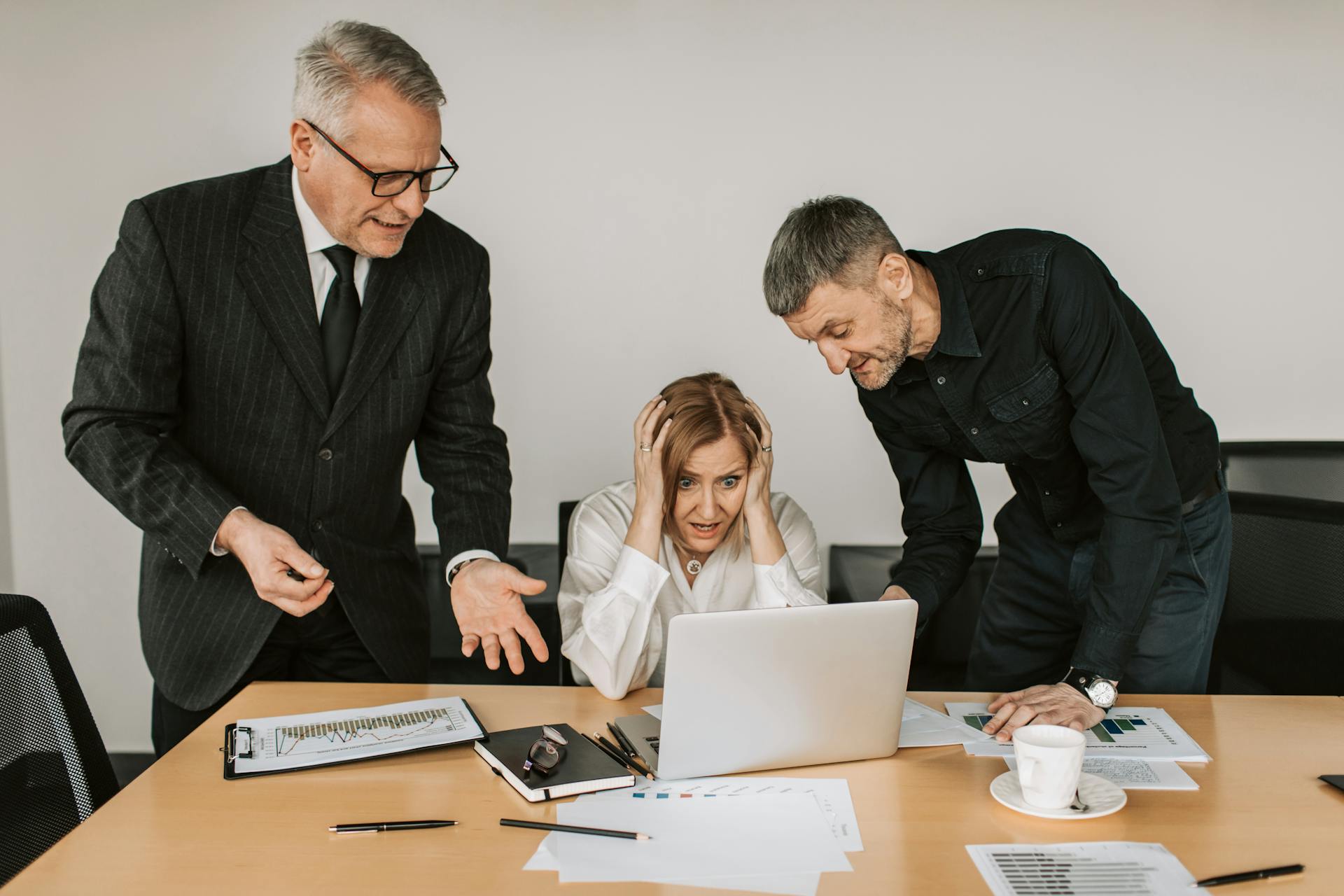 Three business professionals dealing with a stressful situation at work, highlighting workplace tensions.