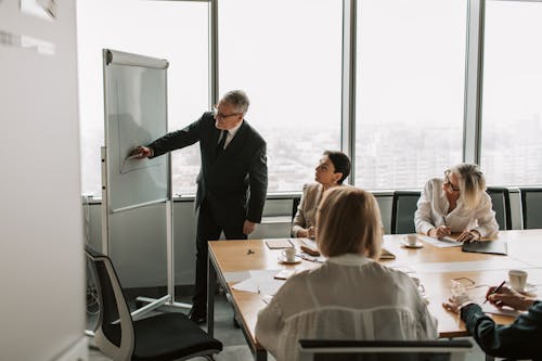 Free Mature Man in Black Suit Drawing on the Whiteboard  Stock Photo