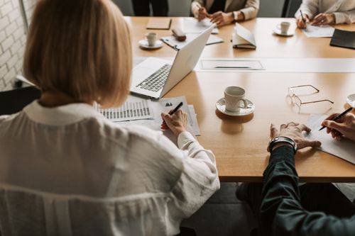 Free Corporate team discussing strategies at a desk with laptops and documents. Stock Photo