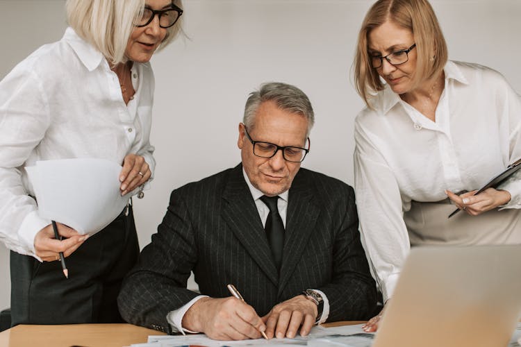 Elderly Man In A Suit Signing A Document