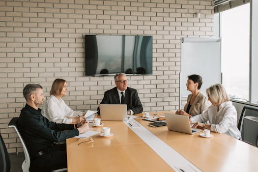 A professional team meeting with laptops and documents in a modern office.