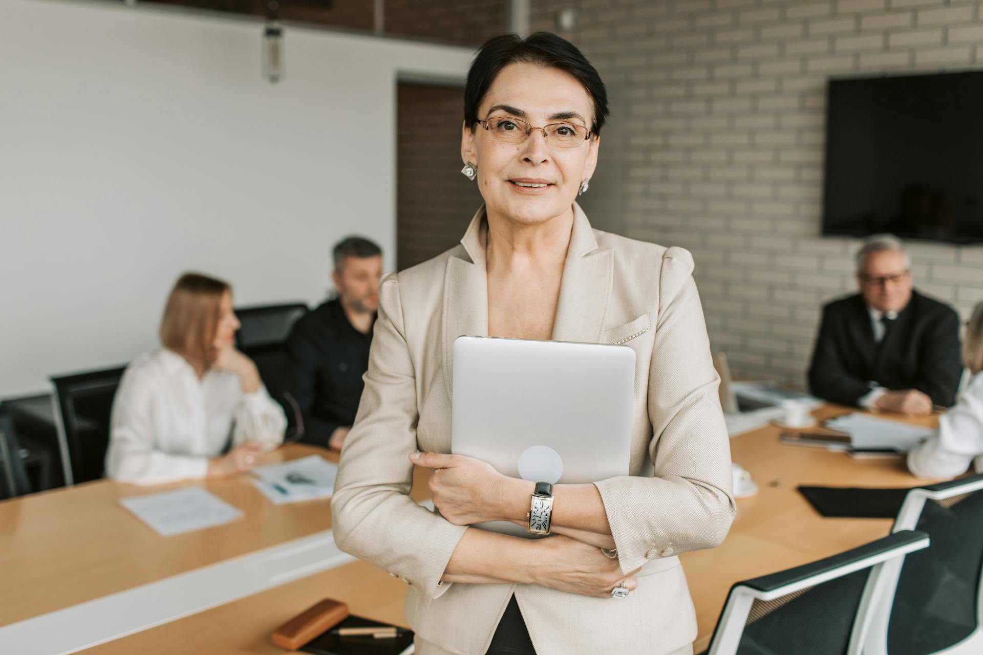 Professional businesswoman holding a tablet in a corporate meeting setting.