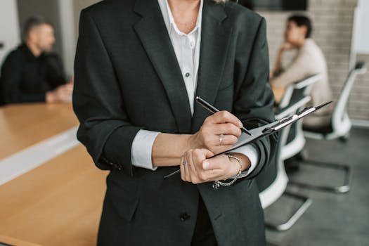 Professional in black suit taking notes during a business meeting.