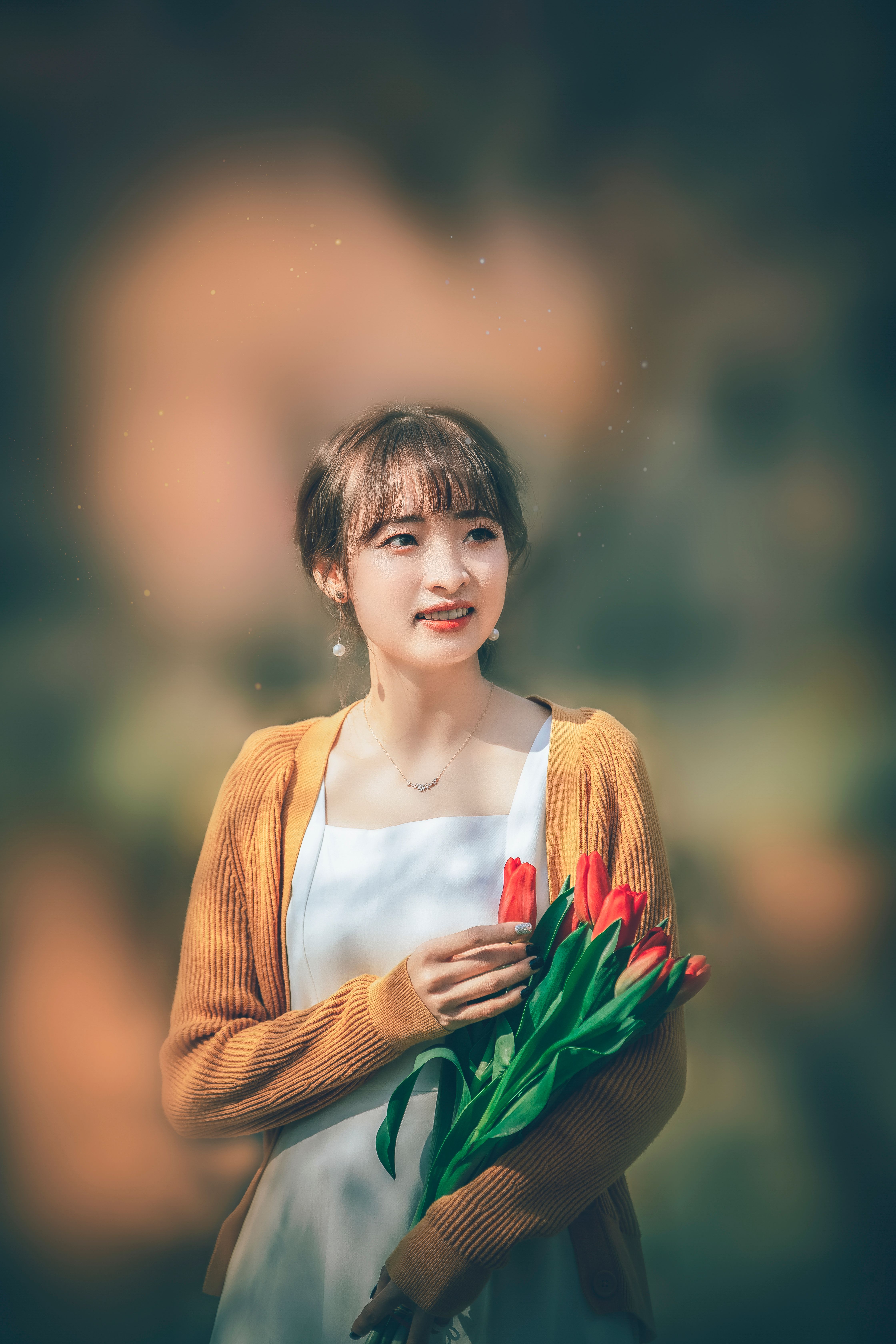 An elegant portrait of a woman holding tulips, captured with soft lighting and a warm background.