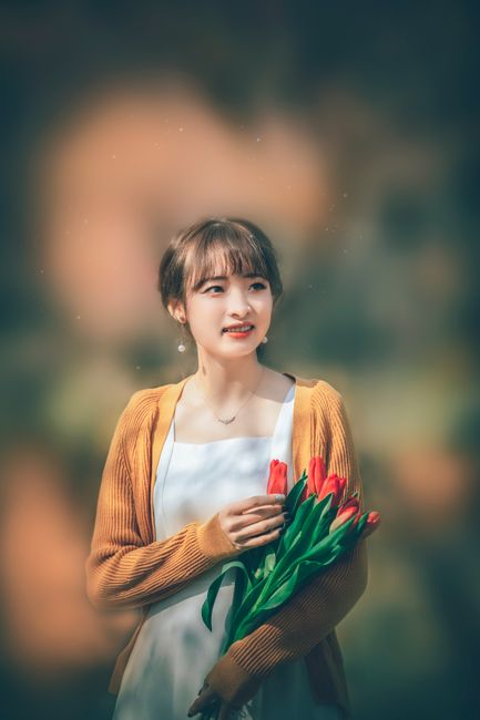 An elegant portrait of a woman holding tulips, captured with soft lighting and a warm background.