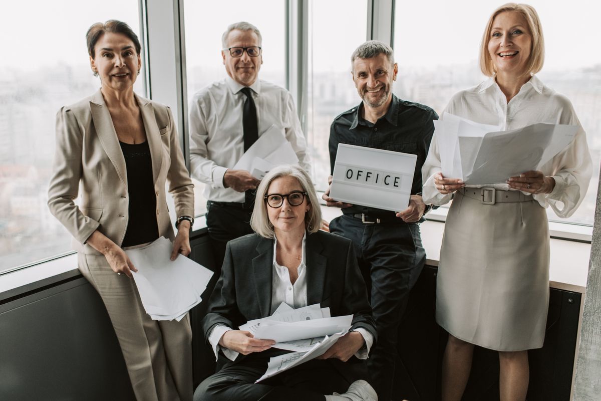 Five colleagues happily collaborating with documents in a modern office setting