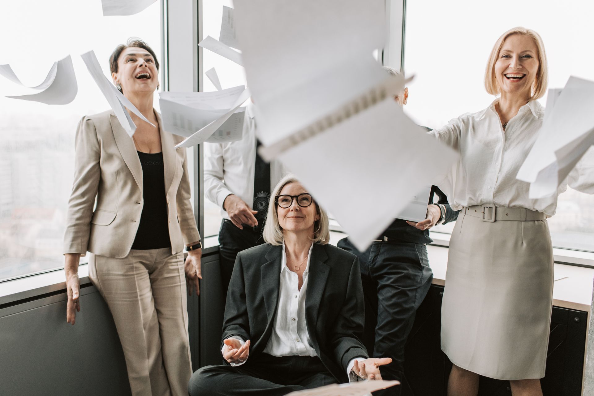 A joyful group of business colleagues celebrates success in a modern office setting.
