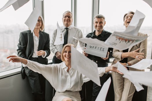 Business team celebrating success with flying papers in modern office setting.