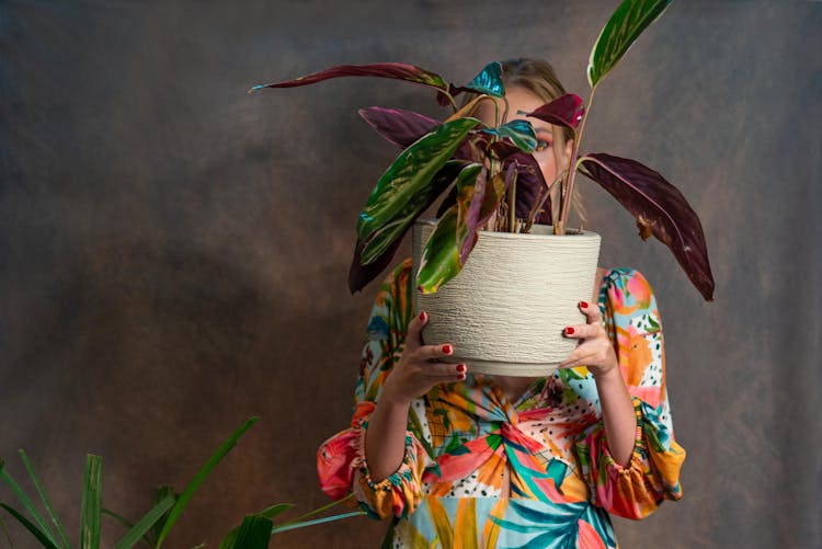 A Woman Holding A Pot With A Plant