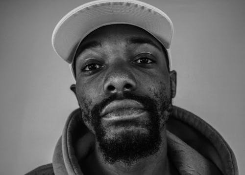 Grayscale Photo of Bearded Man in White Baseball Cap 