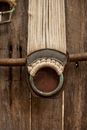 Dirty old belt made of linen ropes with corroded metal ring hanging on timber fence