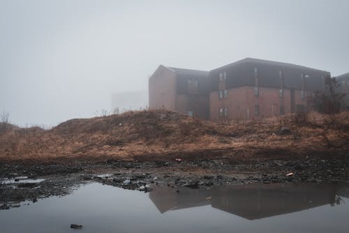 Shabby abandoned house on embankment of dirty lake