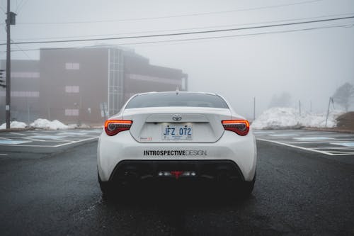 Bumper of stylish sport car on straight roadway in snowy and foggy day