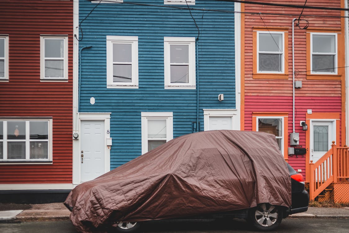 Free Car covered with textile near buildings Stock Photo