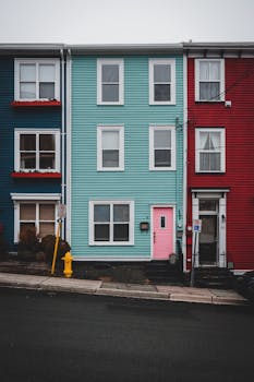 Facade of bright residential houses with windows and door located on street near narrow sidewalk and asphalt roadway in town