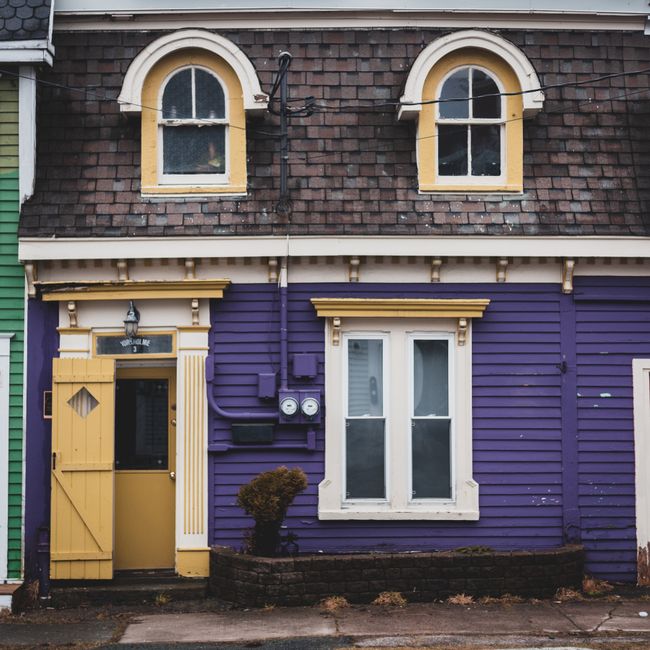 Exterior of multicolored residential house with attics and windows with white frames near doorway