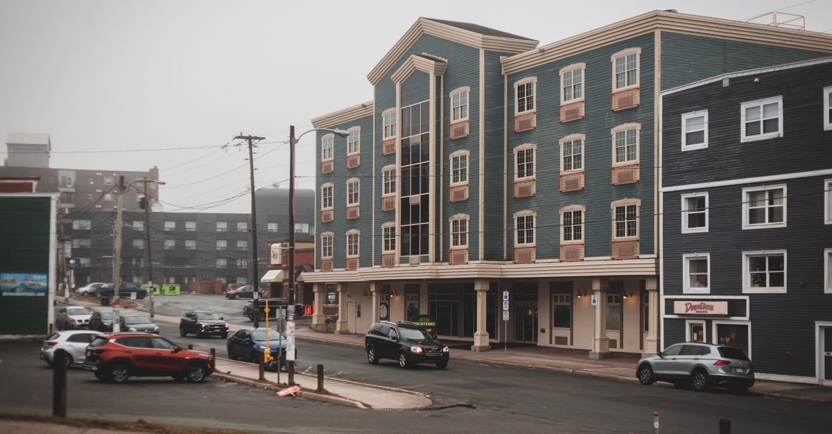 Cars driving on street of city near multistory residential buildings in cloudy day