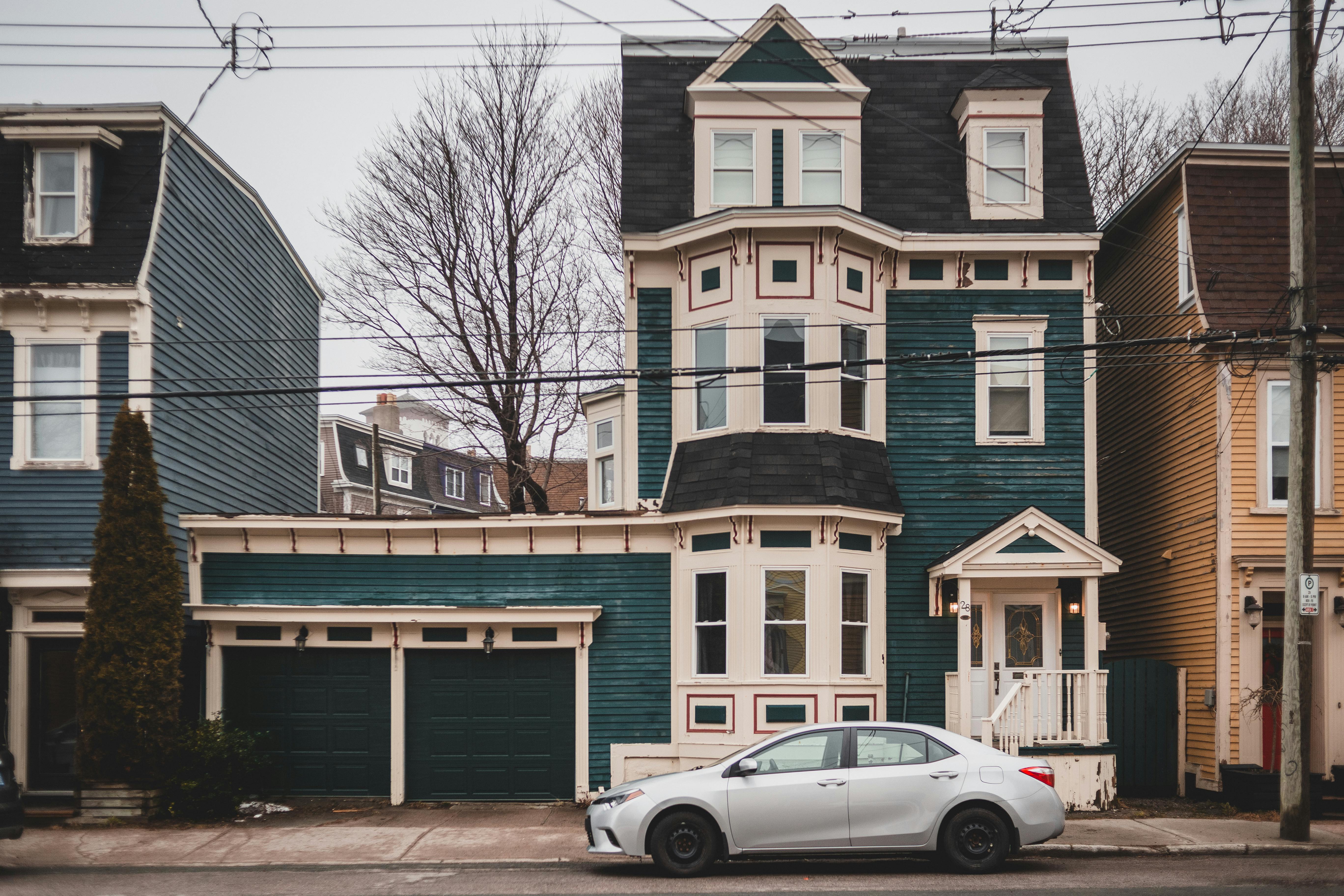 Exterior of aged colorful houses with attics and small windows with car parked on pavement