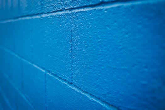 Detailed shot of a bright blue textured brick wall with uneven surfaces and vivid color.