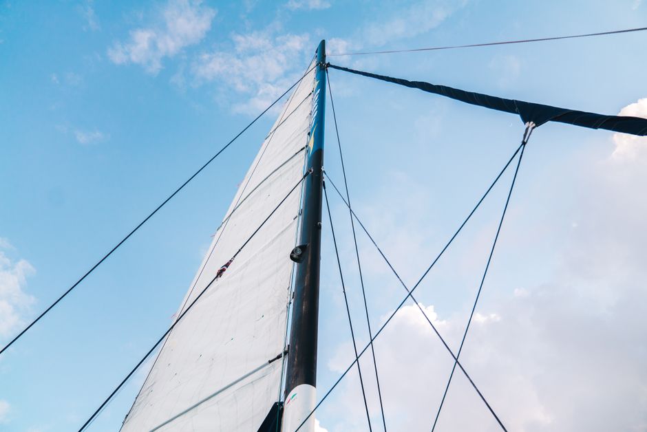 Outstanding Aruba Sunset Sail Cruise Aboard The Dolphin Catamaran Review 2026 - From below of mast with white sail against cloudy blue sky in sunny day