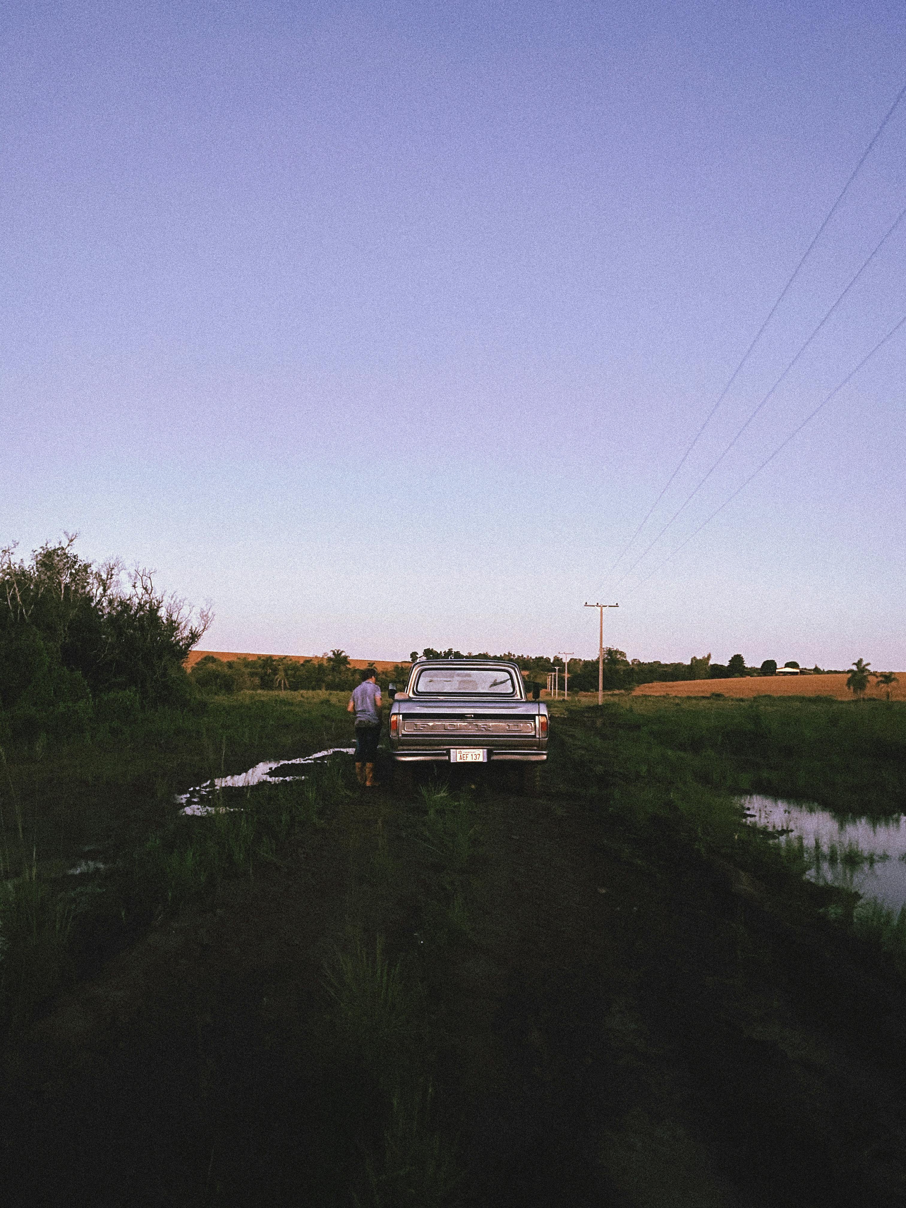 A nostalgic scene of a vintage pickup truck parked on a rural dirt road at sunset.