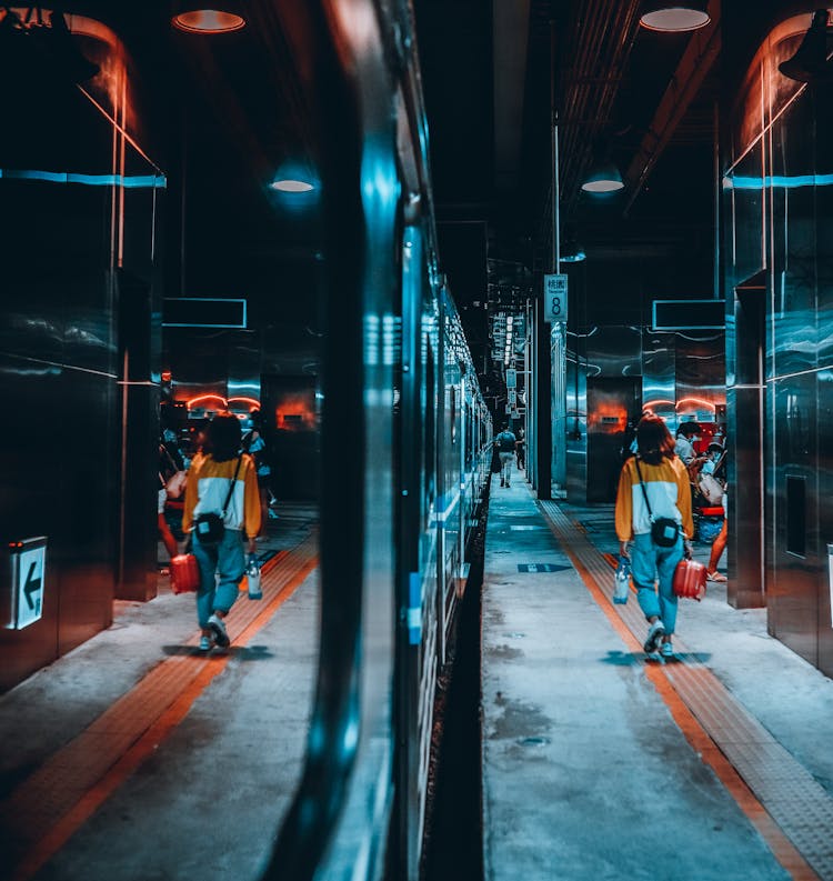 Woman In Sweater And Denim Pants Walking On Night Time Near Train 