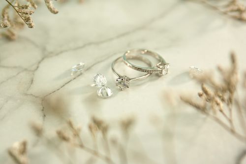 Free High angle of elegant shiny silver rings and precious diamonds placed near twigs on marble table Stock Photo