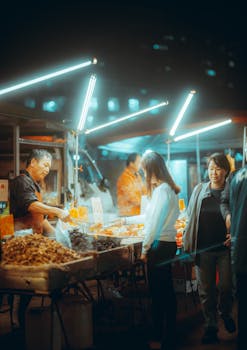 Taiwan street market at night with street vendors and customers engaging in lively transactions.