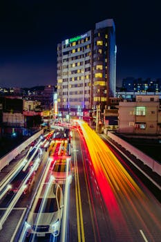 Vibrant cityscape at night with long exposure light trails highlighting urban life.