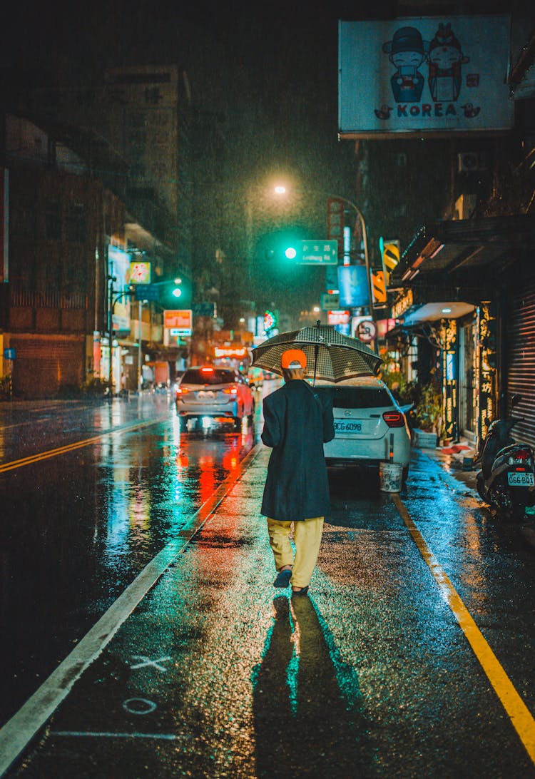 A Person Using An Umbrella At Night