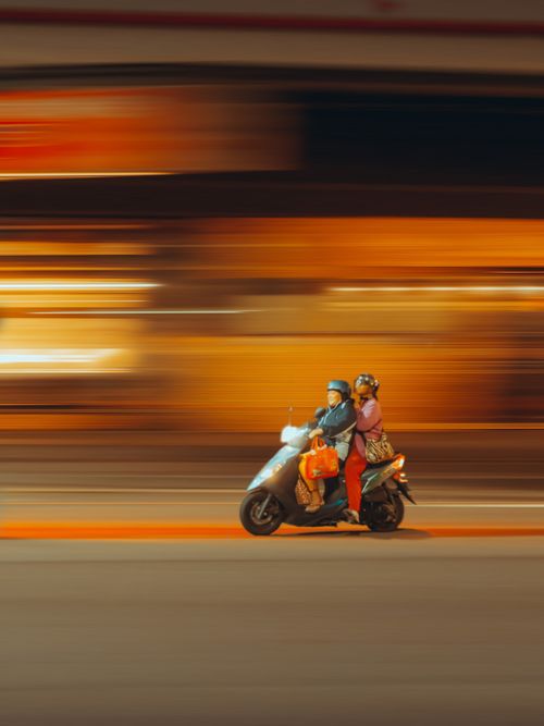 Free Couple riding a motor scooter at night, captured with motion blur highlighting speed and energy. Stock Photo