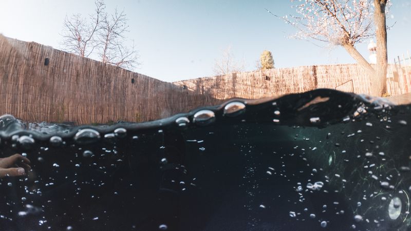 blue bubble solar cover partly pulled back on a backyard in-ground pool