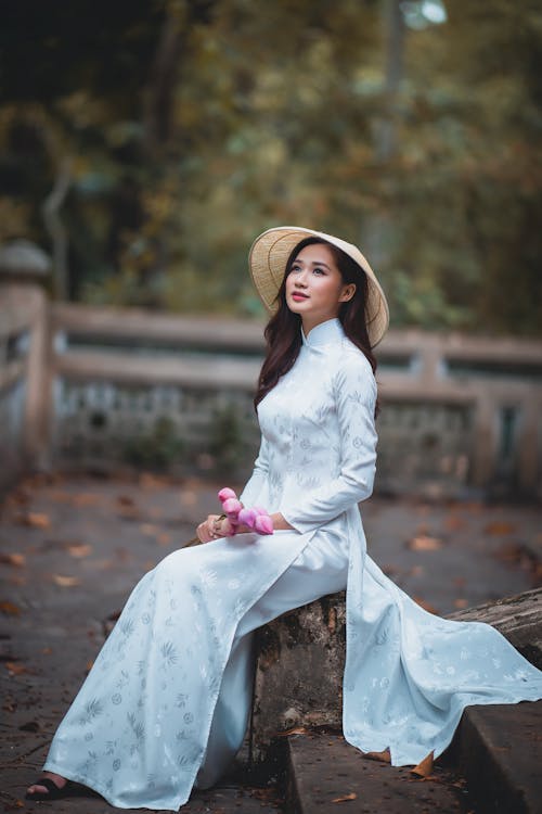 Free Dreamy Asian woman sitting with flowers in park Stock Photo