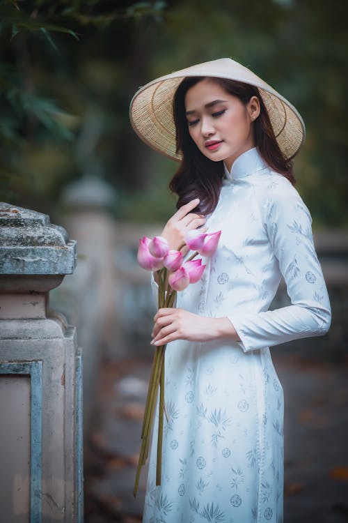 Free Asian lady with bouquet closing eyes in park Stock Photo