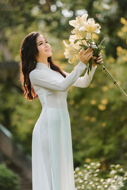 Smiling ethnic lady with bunch of white lilies · Free Stock Photo