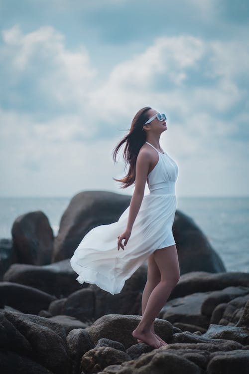 Woman in dress on rocky seashore in summer