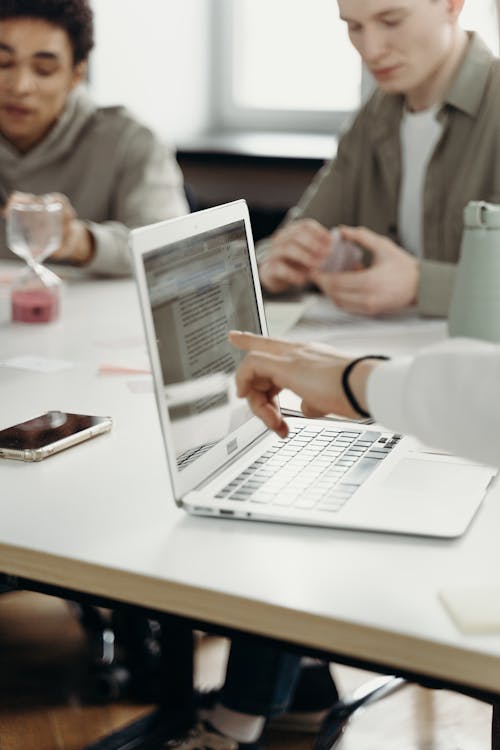 Person in White Long Sleeve Shirt Pointing on Laptop Screen