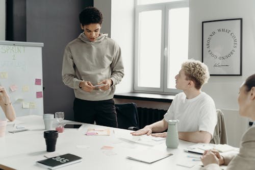 Free Man in Gray Sweater Standing In Front of His Colleagues Stock Photo