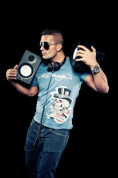 Portrait of a stylish male DJ holding speakers in a studio.
