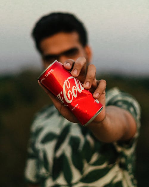 Selective Focus Photo of a Man's Hand Holding a Soda Can