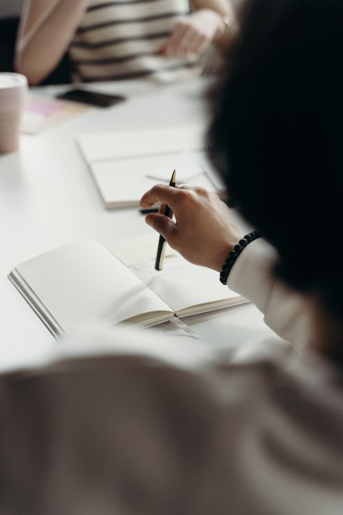 Free Close-up of professionals brainstorming with notebooks during a business meeting. Stock Photo